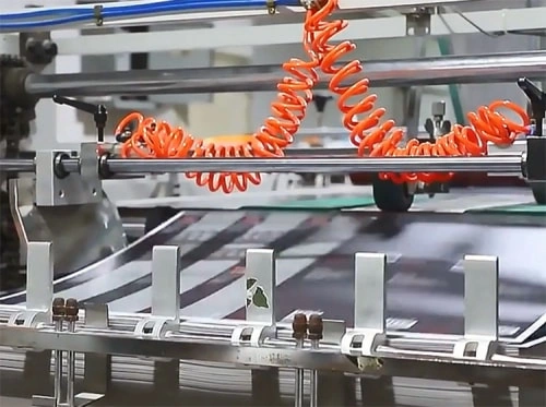 Printed sheets moving through automated packaging finishing equipment